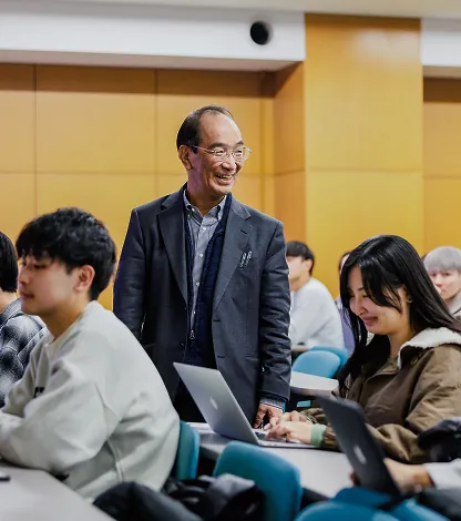 講義室でノートパソコンを使う学生を見守る講師