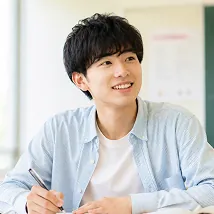 ノートに書き込みながら微笑む男子学生