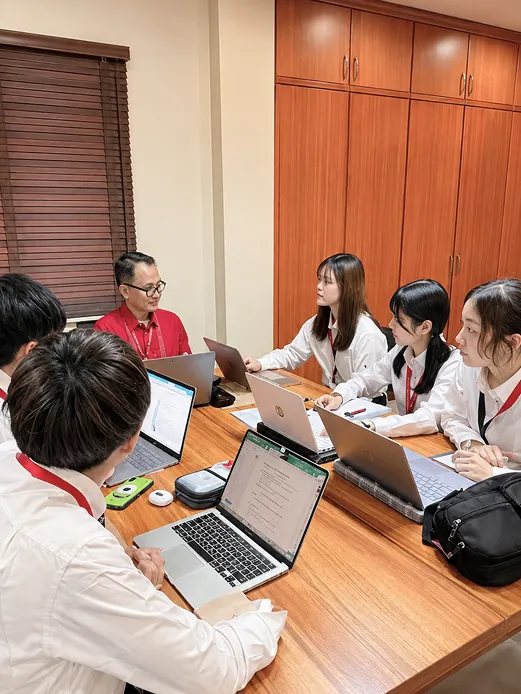 ノートPCを開いてミーティングをする学生たちと指導員