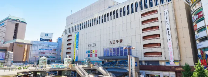 青空のもと建つ八王子駅の駅舎と隣接する商業施設のビル外観