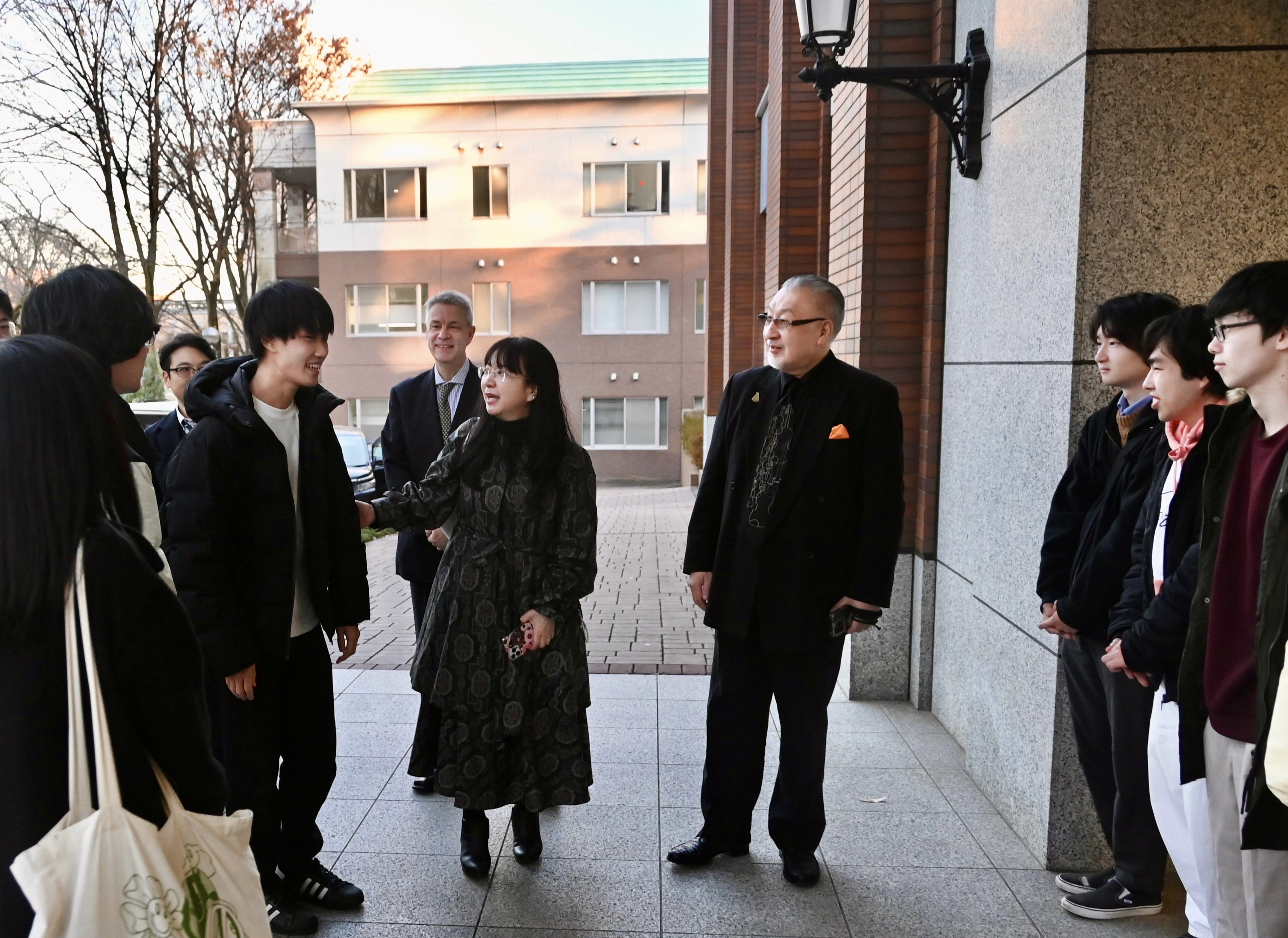 正在欢迎篠崎先生（右）的学生们与负责引导的乌尔班阳子女士（中）