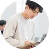 バインダーを持ちながら下を向いて作業する男性