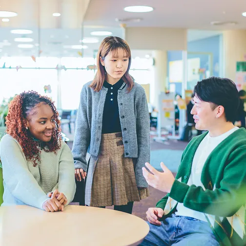 テーブルを囲み会話を楽しむ3人の学生たち