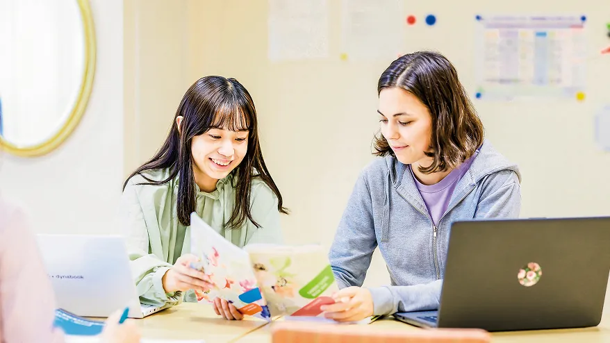 パンフレットを仲良く見つめる2人の女子学生