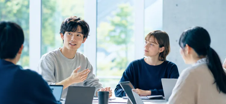 会議室でノートPCを前に真剣な表情でディスカッションを行う男女
