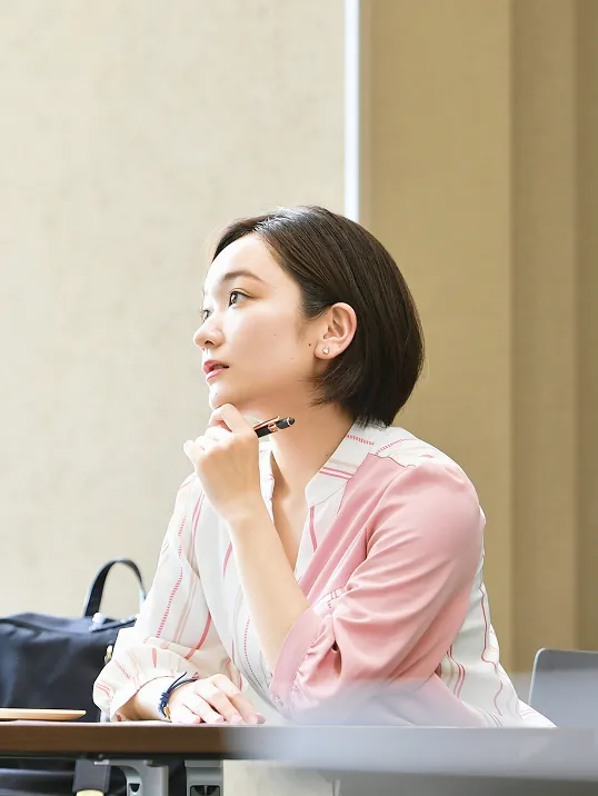 講義中にペンを持ち考え事をする女子学生