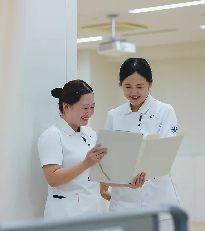 白衣を着て書類を確認し微笑む2人の女性