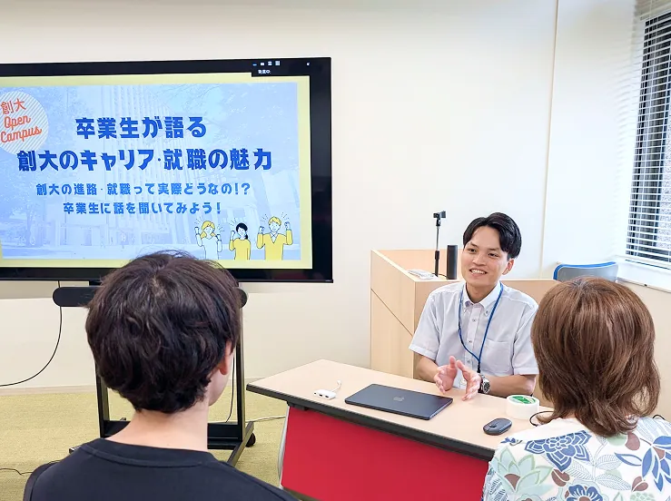 モニターのプレゼンを笑顔で聞く学生たち