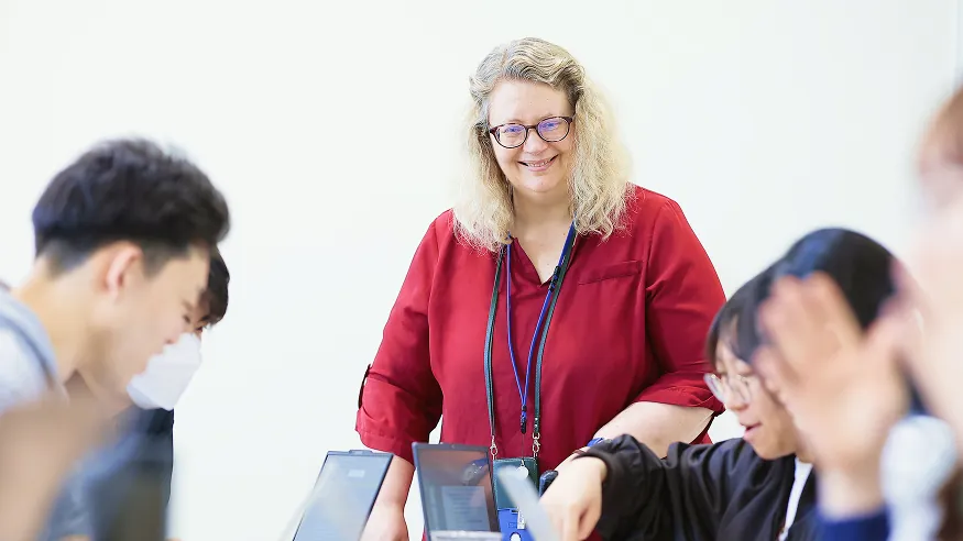 学生たちに囲まれ笑顔で見守る女性講師
