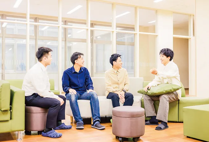 ソファに座ってリラックスした様子で会話を楽しむ男子学生たち