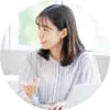 ノートパソコンを開き、笑顔で横を見る女性