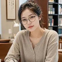 書棚を背景にこちらを見つめるメガネの女子学生