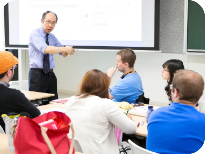 プロジェクターの資料を使い講義を行う教員と熱心に聴講する学生たち